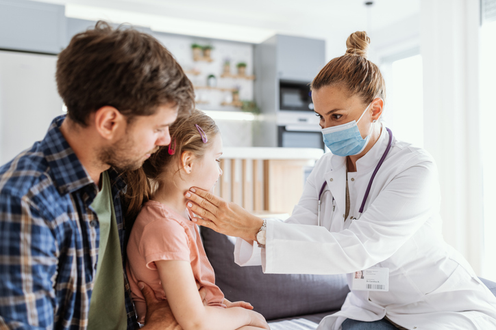 Female doctor visiting sick girl at home and examining her health